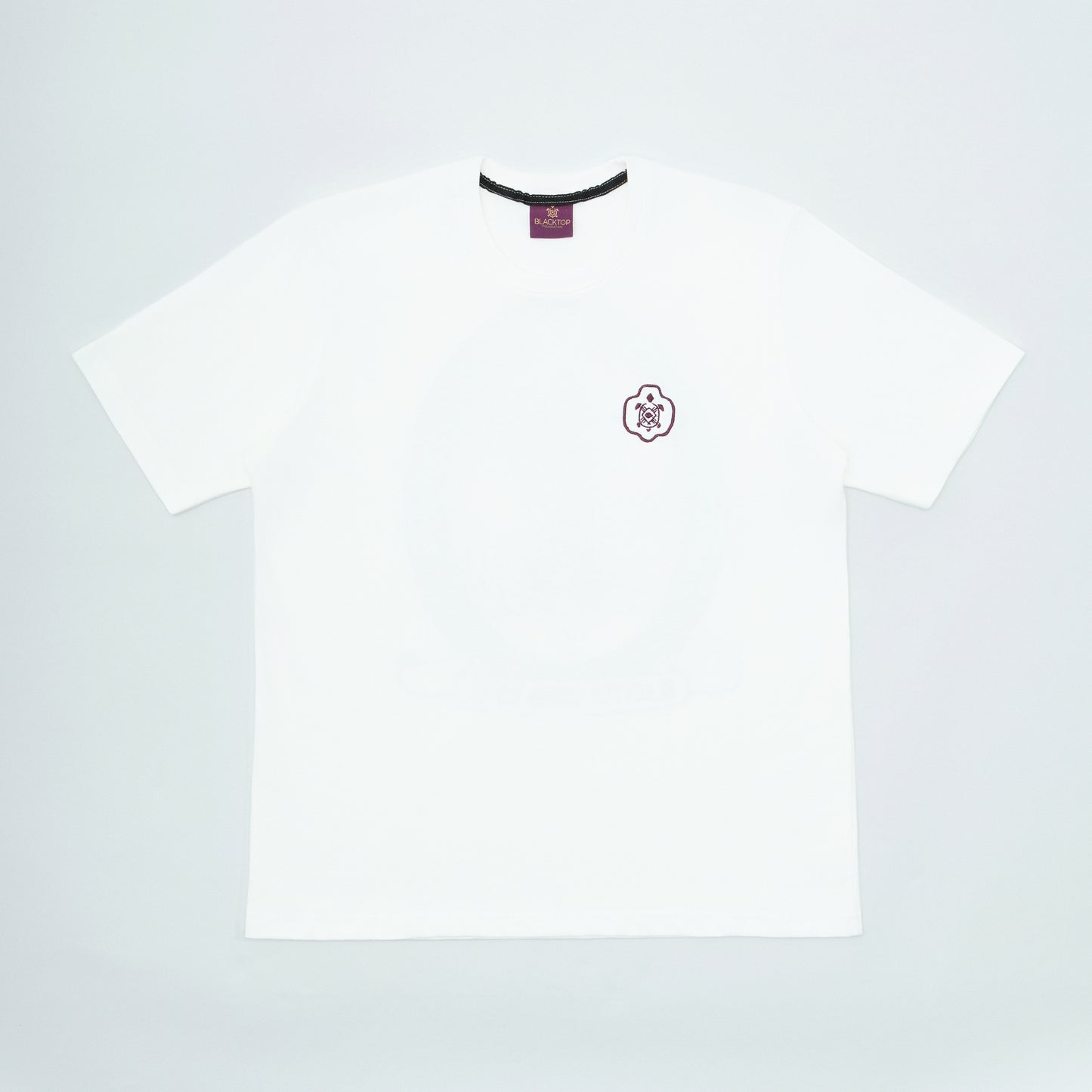 White t-shirt with a small logo on a light gray background