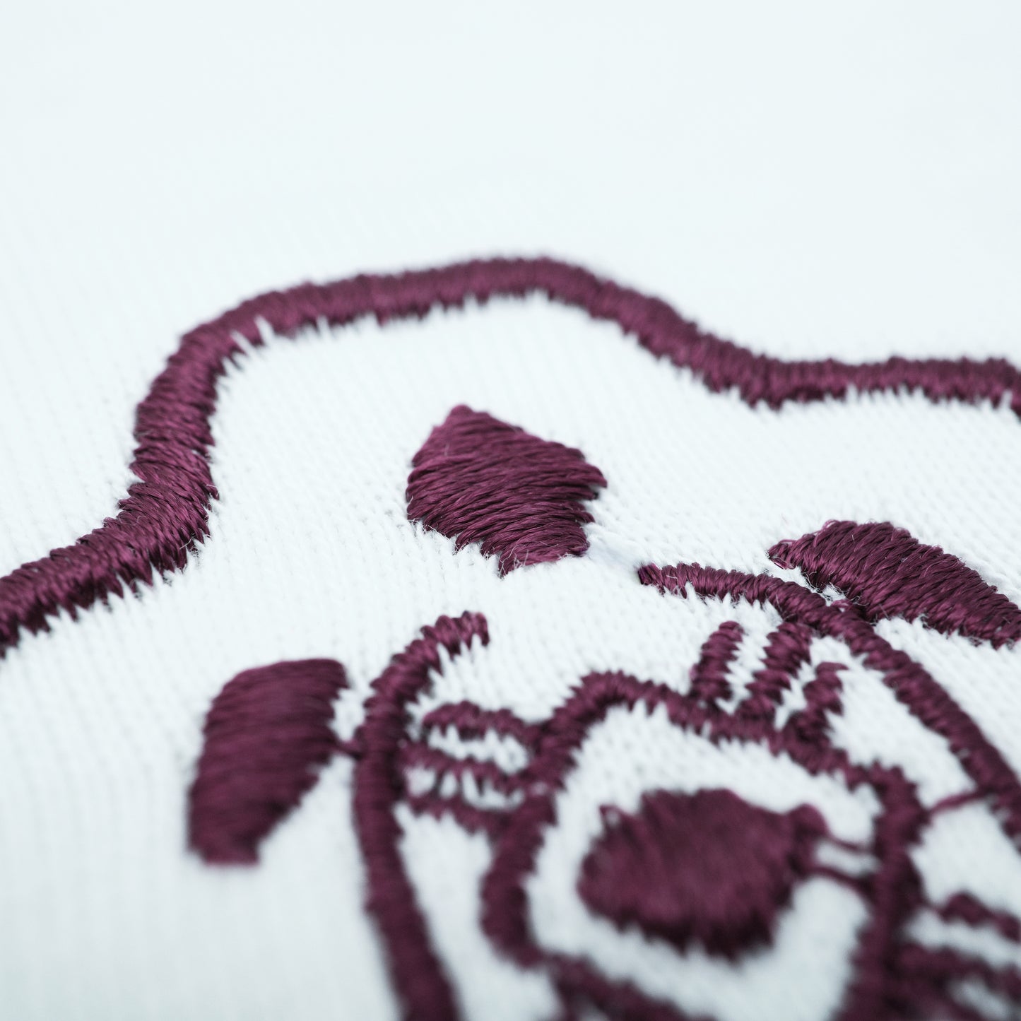 Embroidered design on fabric with a heart and floral elements in purple thread.