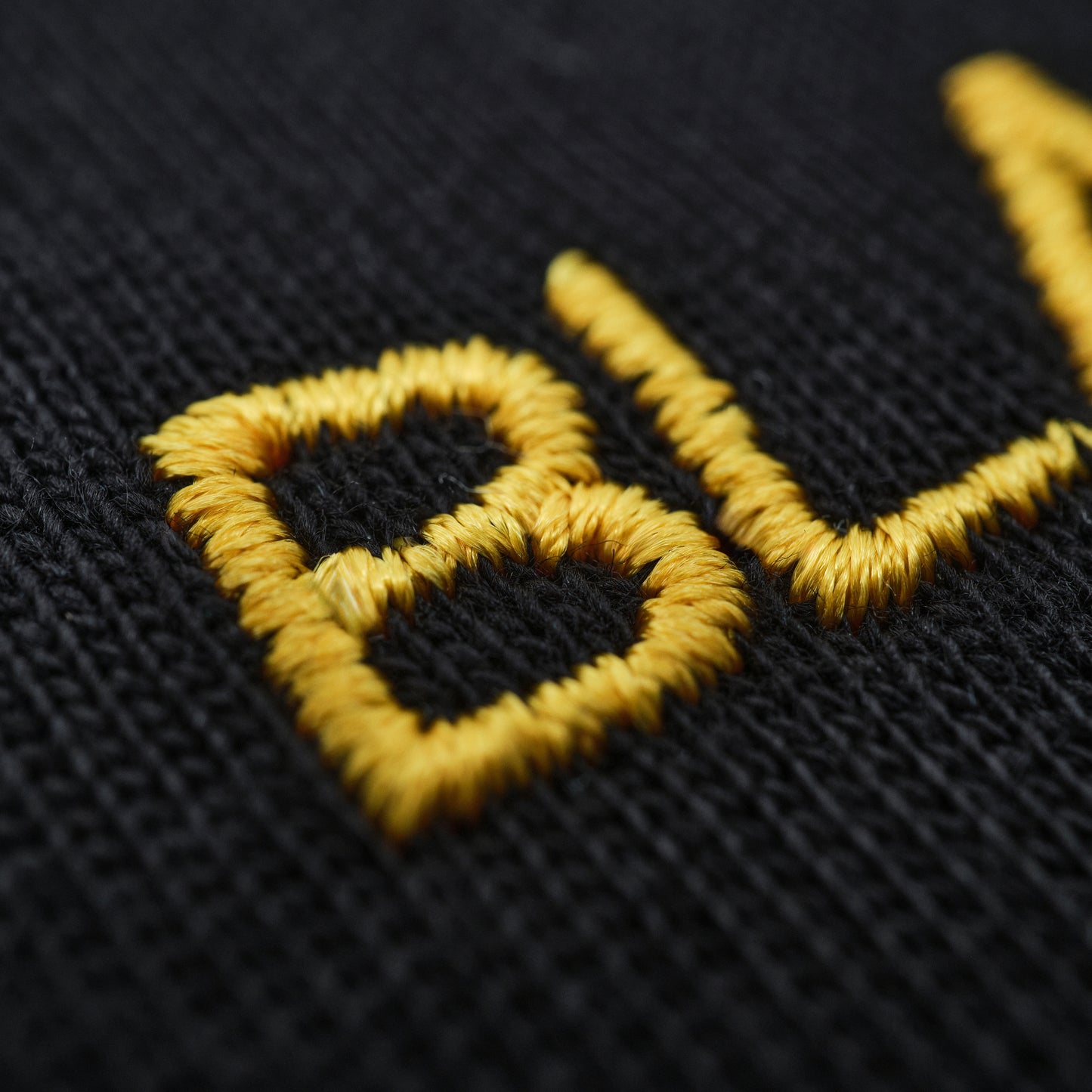 Close-up of yellow embroidered logo on black fabric