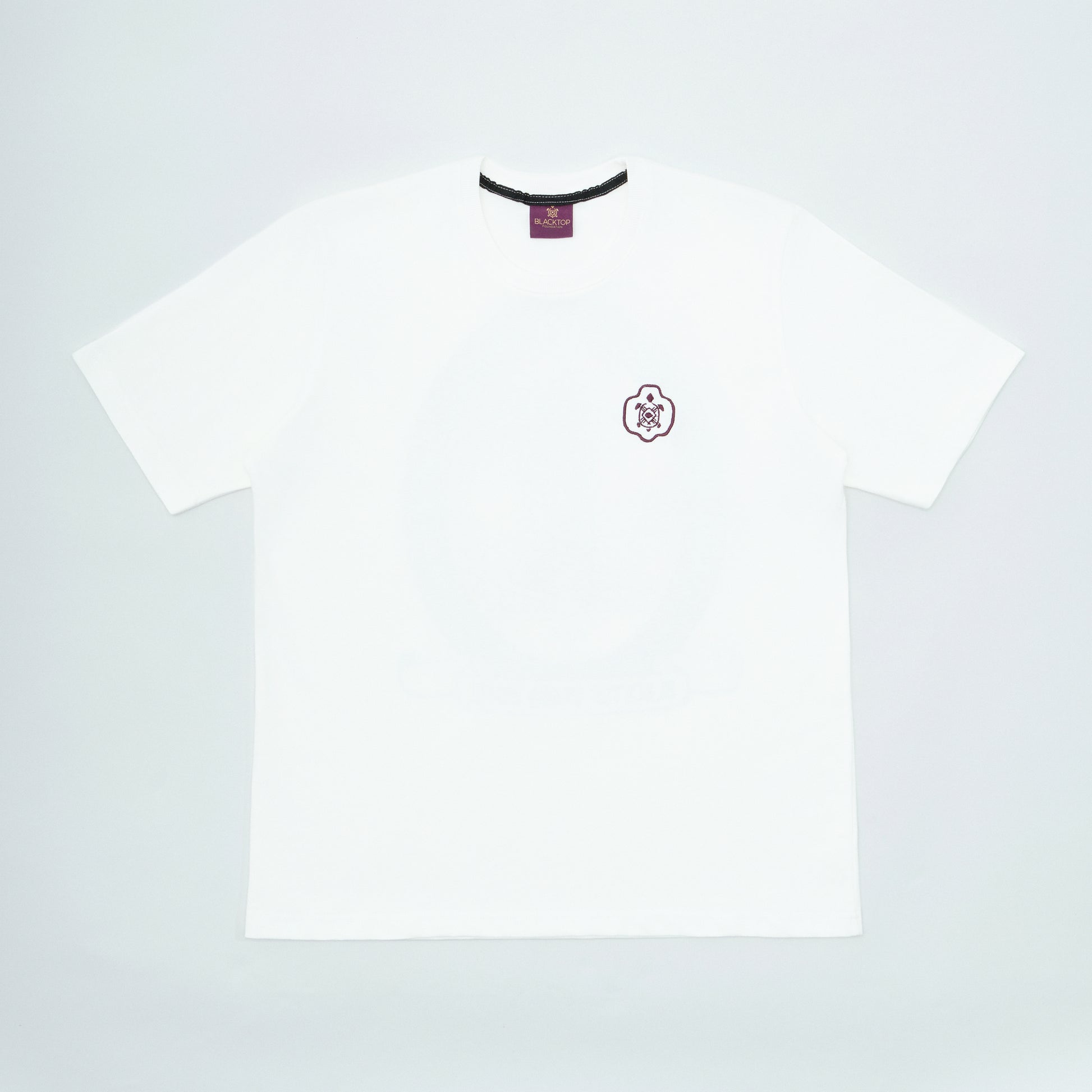 White t-shirt with a small logo on a light gray background