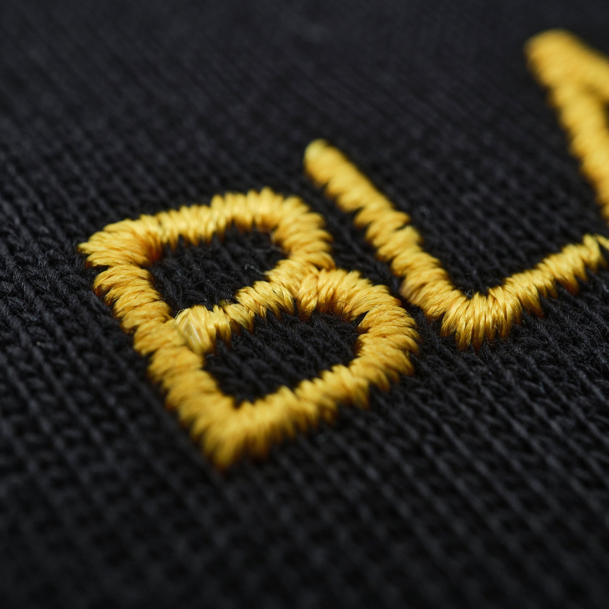 Close-up of yellow embroidered logo on black fabric
