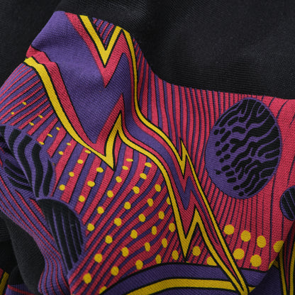 Close-up of a colorful fabric with abstract patterns in red, purple, yellow, and black.